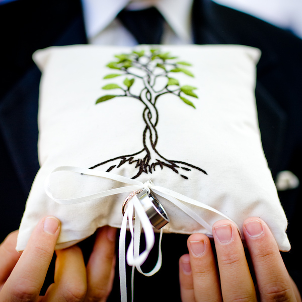 photo of groom holding the ring bearer's pillow with the tree of life design and the wedding rings attached - photo by New Mexico based wedding photographers Twin Lens